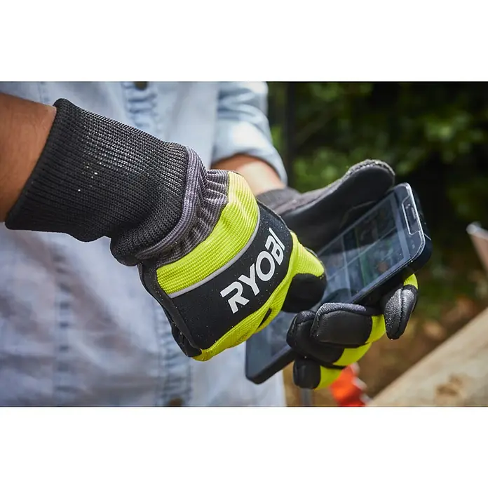Ryobi Schutzhandschuhe RAC258 - M - Nahaufnahme von Händen mit Ryobi-Arbeitshandschuhen, die ein Smartphone halten. Ideal für sicheres Arbeiten mit Touchscreen-Geräten.
