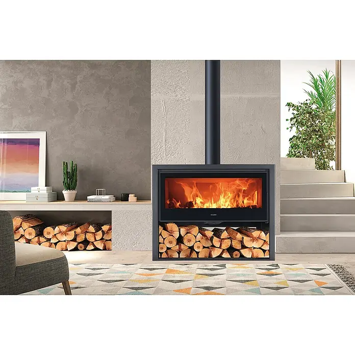 Panadero Kaminofen ALLEGRO - 8,9 kW, Raumheizvermögen: 270 m³, Material Verkleidung: Stahl, Schwarz Metallic - Elegantes Interieur mit einem modernen Kaminofen, der Wärme und Stil in den Raum bringt, ergänzt durch gestapeltes Holz und sanfte Lichtakzente.