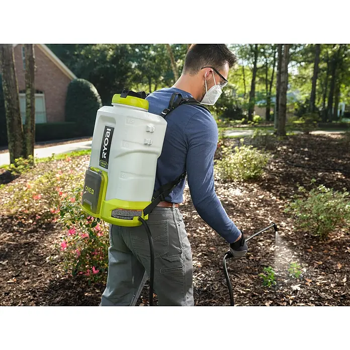 Ryobi ONE+ Akku-Drucksprühgerät 18V RY18BPSB-0 - 18 V, Li-Ionen, Ohne Akku, Betriebsdruck: 3 bar - 6 bar - Ein Mann mit einer Ryobi Akku-Rückenspritze bei der Gartenarbeit. Sie ist weiß mit grünen Akzenten und für den einfachen Gebrauch konzipiert.