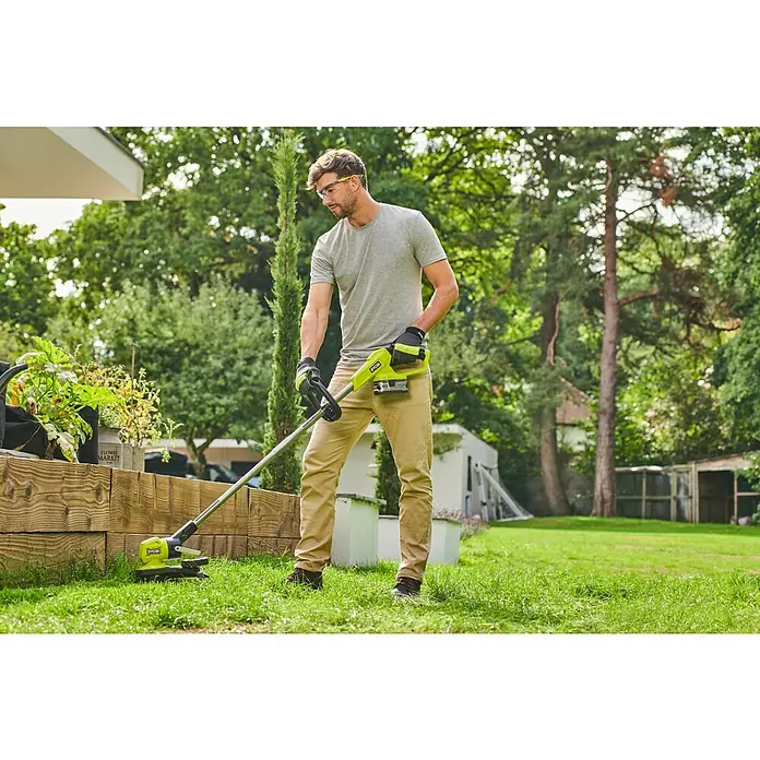 Ryobi ONE+ Akku-Rasentrimmer RY18LT33A - 18 V, Ohne Akku - Ein Mann benutzt einen Ryobi Rasentrimmer im Garten, um Rasen zu trimmen. Der Akku-Rasentrimmer ist gelb und schwarz.