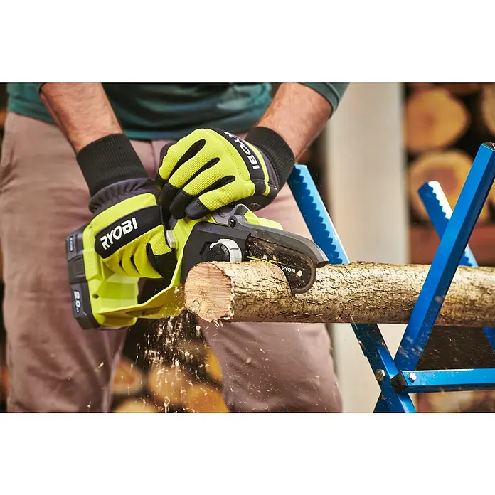 Ryobi ONE+ Akku-Astsäge RY18PSX10A-0 - 18 V, Li-Ionen, Ohne Akku, Schwertlänge: 10 cm - Nahaufnahme einer Person, die mit einer RYOBI Akku-Kettensäge ein Holzstück auf einem blauen Sägebock zuschneidet.