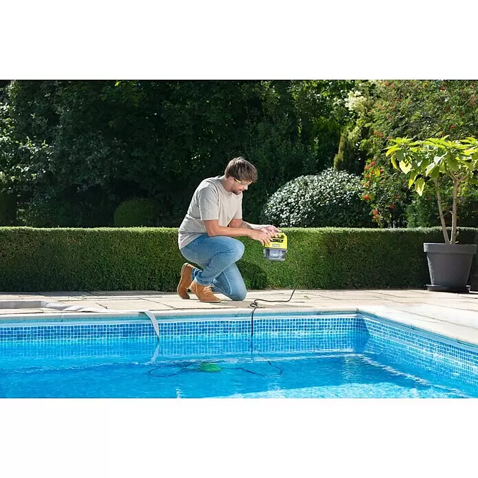 Ryobi ONE+ Bomba para aguas residuales - Capacidad de bombeo máx.: 4.200 l/h - Hombre arrodillado junto a una piscina, manejando un limpiafondos Ryobi amarillo y gris conectado a un dispositivo en el agua.