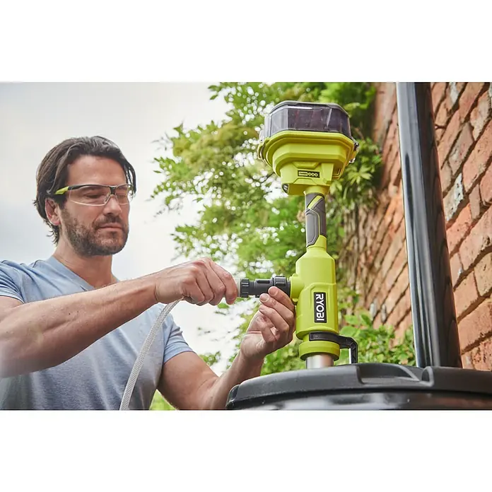 Ryobi ONE+ Akku-Regenfasspumpe RY18STPA-0 - Max. Fördermenge: 3.360 l/h - Ein Mann schließt einen Schlauch an eine Ryobi-Wasserpumpe an, die auf einem schwarzen Tank steht.
