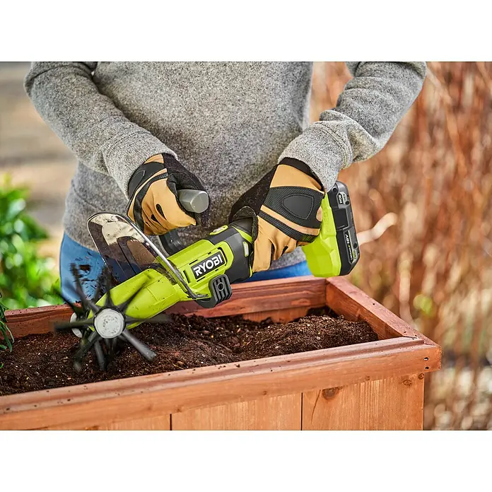 Ryobi ONE+ Akku-Bodenhacke RY18HCA-0 - 18 V, Ohne Akku - Nahaufnahme eines Akku-Bodenbearbeitungsgeräts von Ryobi, das in einem Hochbeet verwendet wird.