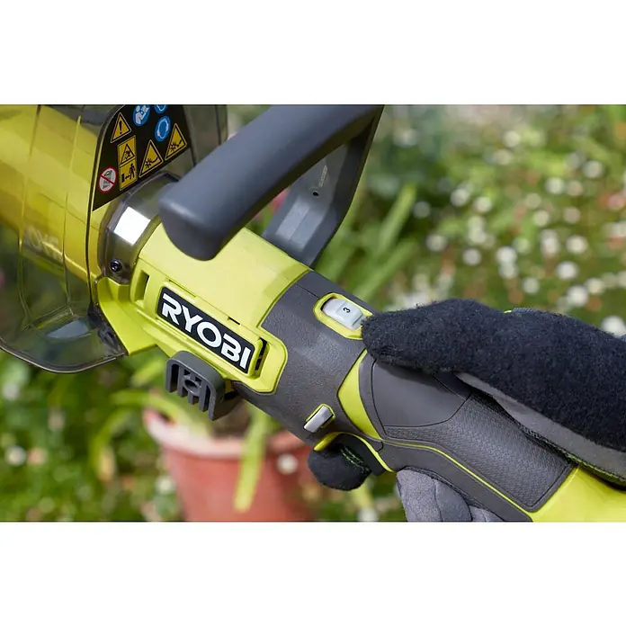 Ryobi ONE+ Akku-Bodenhacke RY18HCA-018 V, Ohne Akku - Nahaufnahme einer Ryobi Heckenschere, die von einer behandschuhten Hand bedient wird. Die Bedienelemente der Heckenschere sind gut sichtbar.