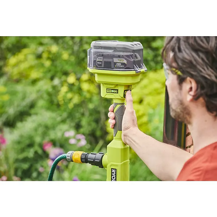 Ryobi ONE+ Akku-Regenfasspumpe RY18STPA-0 - Max. Fördermenge: 3.360 l/h - Akkubetriebener Bewässerungstimer von Ryobi mit transparentem Gehäuse, montiertem Akku und angeschlossenem Gartenschlauch im Außenbereich.