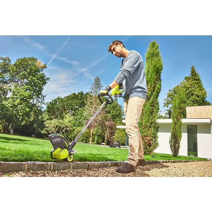 Ryobi ONE+ Akku-Rasentrimmer RY18LT33A - 18 V, Ohne Akku - Ein Mann benutzt einen Ryobi Rasentrimmer, um Rasenkanten zu pflegen. Der Trimmer in Grün und Schwarz steht auf einem gepflasterten Weg.