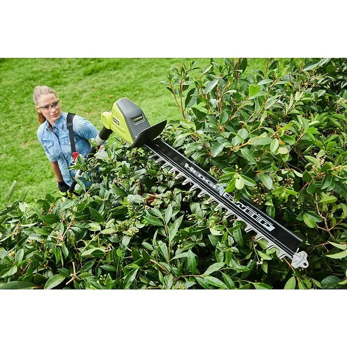 Ryobi Max Power Teleskop-Heckenschere RY36PHT50A-0 - 36 V, Li-Ionen, Anzahl Akkus: Ohne Akku - Eine Frau benutzt eine Ryobi Heckenschere, um eine Hecke zu schneiden. Das Gerät hat eine lange Klinge und einen grünen Griff.