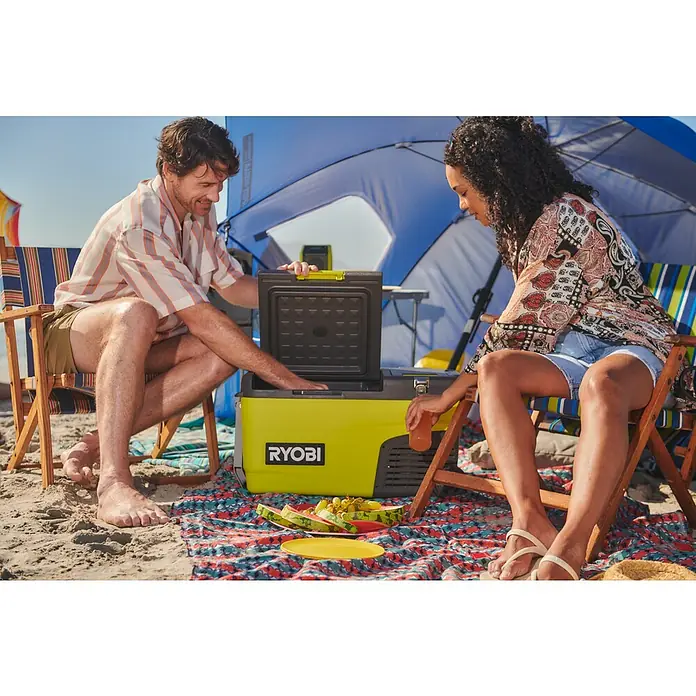 Ryobi ONE+ Akku-Kühlbox Hybrid RY18CB23A-0 - L x B x H: 72,5 x 42 x 49,5 cm, Fassungsvermögen: 23 l - Eine tragbare RYOBI-Kühlbox in Limettengrün wird von zwei Personen am Strand benutzt, um Getränke und Speisen zu lagern.