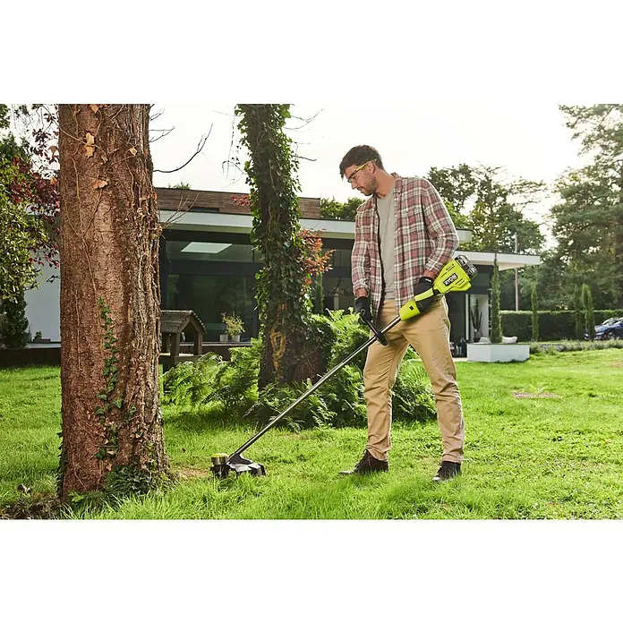 Ryobi ONE+HP Akku-Rasentrimmer RY18LTX38A-0 - 18 V, Li-Ionen, Ohne Akku - Ein Mann benutzt einen Ryobi Rasentrimmer im Garten, um Gras um einen Baum herum zu schneiden.