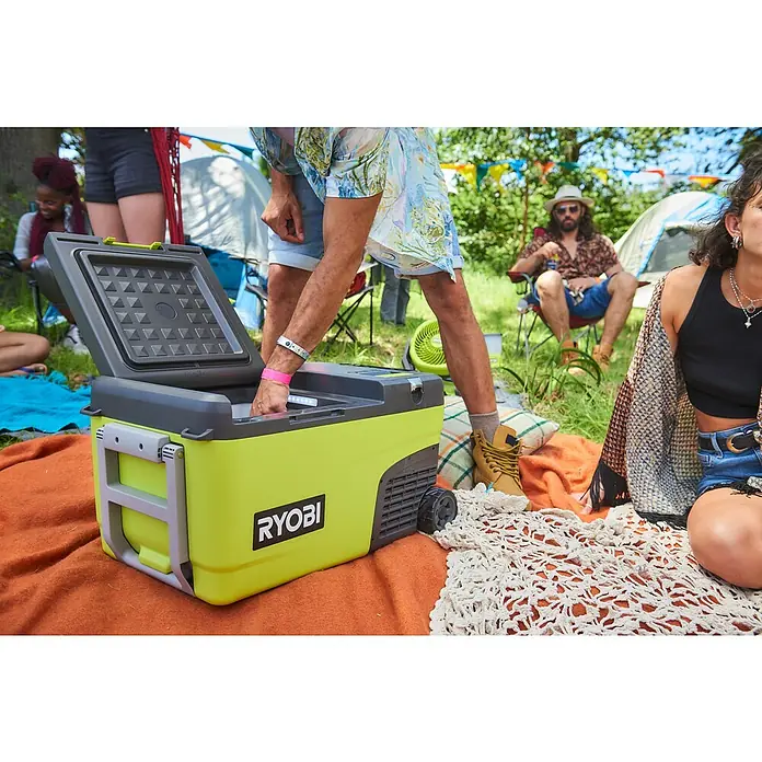 Ryobi ONE+ Akku-Kühlbox Hybrid RY18CB23A-0 - L x B x H: 72,5 x 42 x 49,5 cm, Fassungsvermögen: 23 l - Ein Ryobi Kühlbox im Freien, mit offenem Deckel, umgeben von Personen und Campingausrüstung. Ideal für Campingausflüge und Outdoor-Aktivitäten.