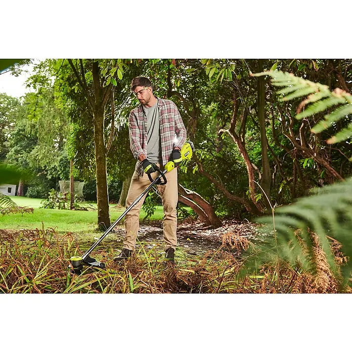 Ryobi ONE+HP Akku-Rasentrimmer RY18LTX38A-0 - 18 V, Li-Ionen, Ohne Akku - Ein Mann benutzt einen gelben und schwarzen RYOBI Rasentrimmer im Garten, um das Gras zu trimmen. Er trägt Schutzbrille, Handschuhe und eine karierte Jacke.