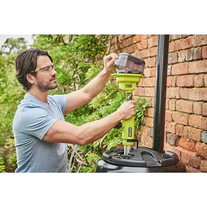 Ryobi ONE+ Akku-Regenfasspumpe RY18STPA-0 - Max. Fördermenge: 3.360 l/h - Ein Mann bedient eine RYOBI-Wasserpumpe, um Wasser aus einem Tank zu befördern. Er trägt dabei eine Schutzbrille für sicheres Arbeiten.