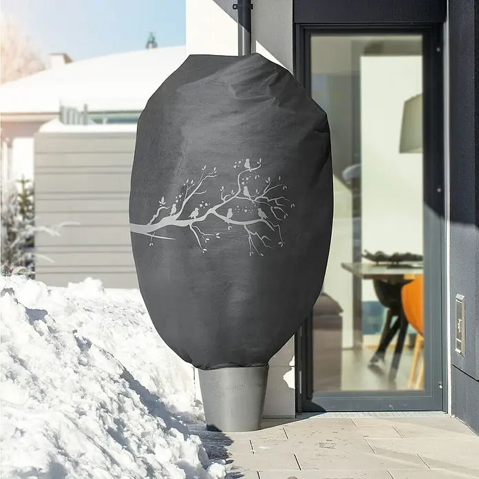 Windhager Abdeckhaube Protect - Vogel, XXL, L x B: 1,4 x 2 m, Grau - Ein grauer Regentonnenbezug mit Vogelbaum-Design schützt eine Regentonne vor Schnee im Winter und fügt sich in die Umgebung ein.