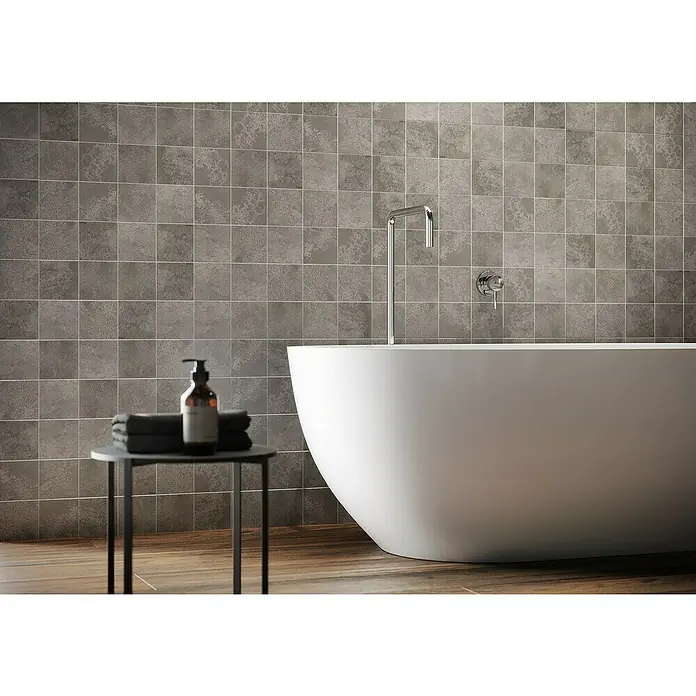 Queens Mosaikfliese 5 x 5 - 29,8 x 29,8 cm, Grau, Matt - Elegantes Badezimmer mit freistehender Badewanne, grauen Fliesen und Holzboden. Die Badewanne ist das zentrale Element des Raumes.