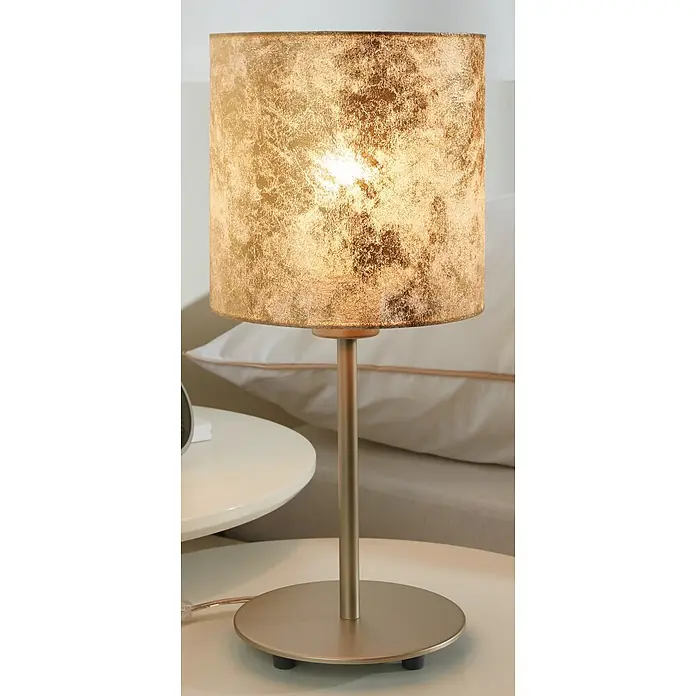 Eglo Viserbella Tischleuchte - 60 W, Champagner, E27 - Nahaufnahme einer goldenen Tischleuchte mit zylindrischem Lampenschirm auf einem Nachttisch, die ein warmes, diffuses Licht ausstrahlt.