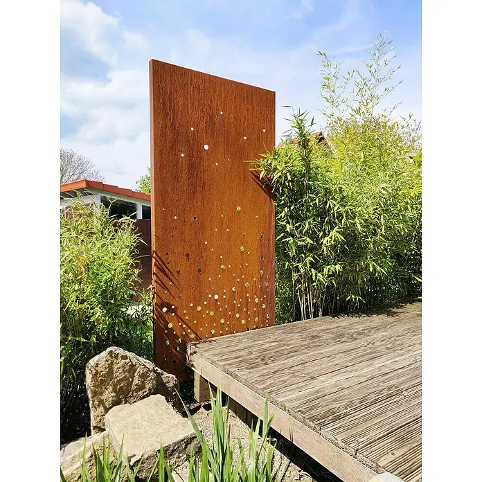 Palatino Space Vertical Sichtschutzelement Vapor - 99 x 180 cm - Gartenblick mit einer dekorativen Roststahlwand mit Löchern, umgeben von Grünpflanzen und einer Holzterrasse.
