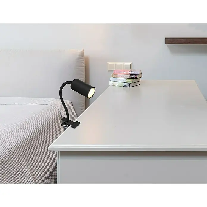 Globo Robby Klemmleuchte25 W, L x B x H: 29 x 10 x 41,5 cm, Farbe Gehäuse: Schwarz, GU10 - Nahaufnahme einer modernen, schwarzen Klemmleuchte auf einem Nachttisch, die ein warmes Licht ausstrahlt. Ideal zum Lesen im Bett.