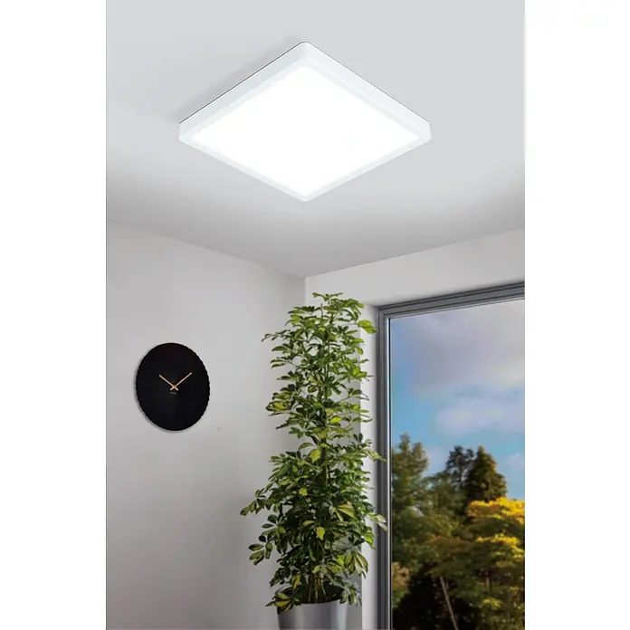 Eglo connect.z LED-Deckenleuchte FUEVA-Z - 19,5 W, L x B x H: 28,5 x 28,5 x 2,8 cm, Weiß, Eckig - Diese Aufnahme zeigt eine moderne, quadratische Deckenleuchte mit LED-Technologie in einem stilvollen Interieur mit Zimmerpflanze und Uhr.