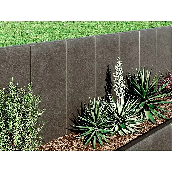 Diephaus L-SteinUnbewehrt, Höhe: 80 cm, Breite: 40 cm, Stärke: 7 cm, Anthrazit - Dunkelgraue Betonmauer mit vertikalen Paneelen, die einen modernen Gartenbereich mit Grünpflanzen und Mulch umgibt.