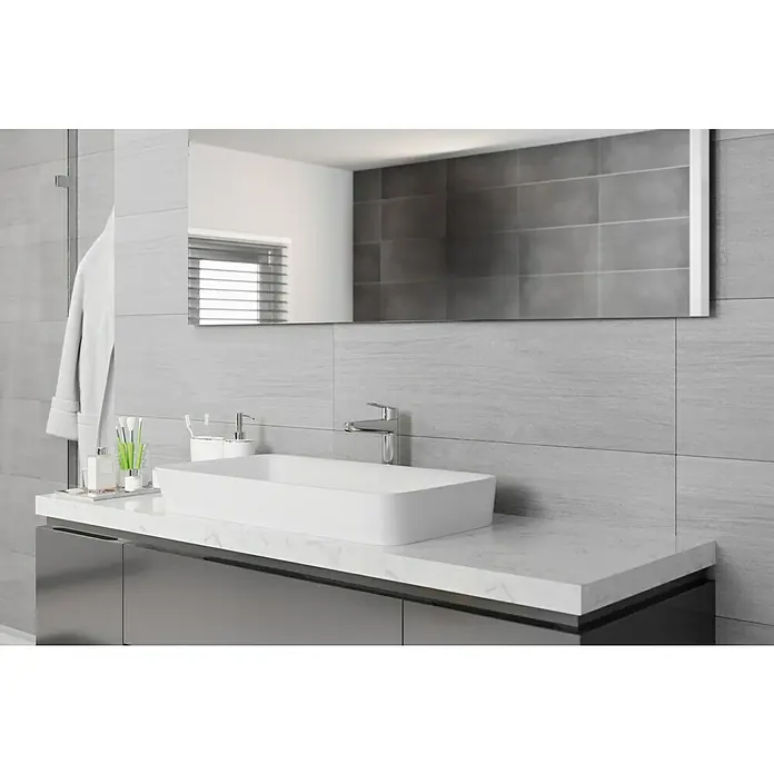 Wandfliese Spa Perla Base - 30 x 90 cm, Grau, Matt - Helles Badezimmer mit einem modernen Aufsatzwaschbecken, Armaturen und einem großen Spiegel, der das Design des Raumes hervorhebt.