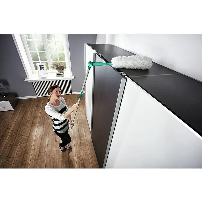 Leifheit Staubwedel Duster XL - Länge: 38 cm, Mikrofaser - Eine Frau wischt Staub von der Oberseite eines Schranks mit einem Leifheit-Staubwedel, der einen Teleskopstiel und einen flauschigen Kopf hat.