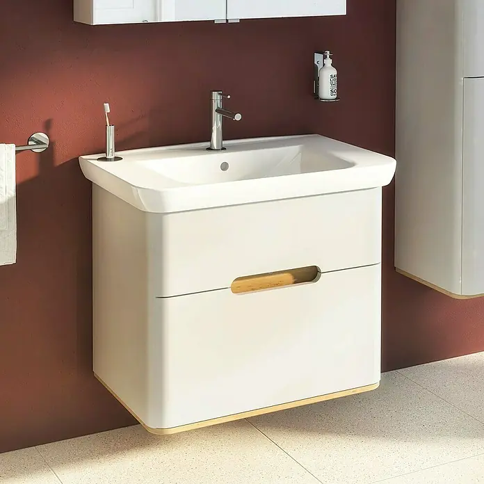 VitrA Sento Badmöbel-Set - 80 cm, Hellgrau, 2 Schubladen, Ohne Wäschekorb - Eine Nahaufnahme eines weißen Badezimmerwaschtisches mit Schubladen und Armatur vor einer kastanienbraunen Wand.