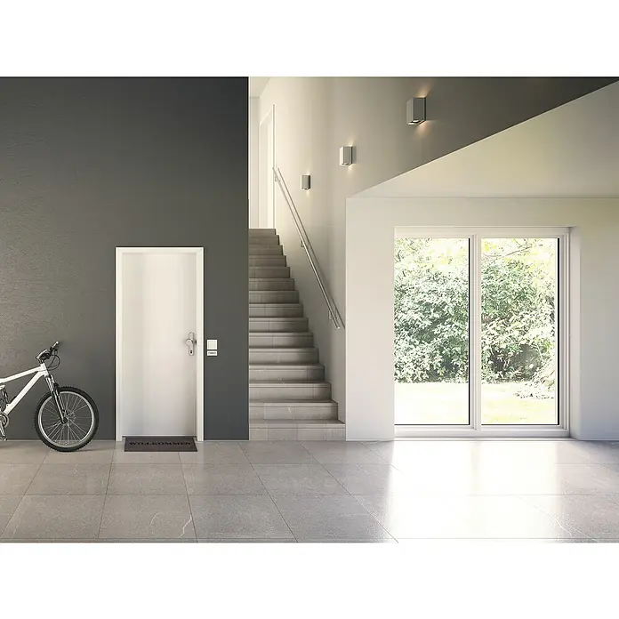 GetaDoor Laminit Wohnungseingangstür GL 223 - Klimaklasse nach RAL: III, 985 x 2.110 mm, DIN Anschlag: Rechts, Weiß seidenmatt - Eingangsbereich mit weißer Tür, Treppe und Fenster. Ein Fahrrad steht an der Wand, und eine Fußmatte liegt vor der Tür.