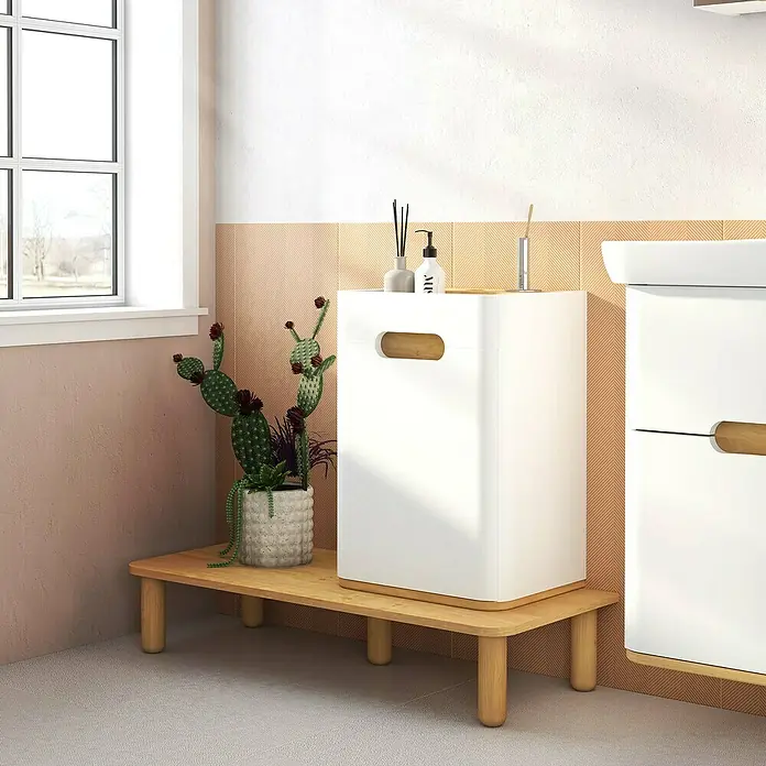 VitrA Sento Halbhochschrank - B x T x H: 40 x 29,5 x 58 cm, Weiß, DIN Anschlag: Links - Ein Badezimmer-Setup mit einem weißen Schrank mit Holzgriffen auf einem Holzständer neben einer Fensterbank und einer Kaktuspflanze.