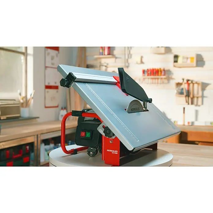 Herkules Elektro-Fliesenschneider H-FS 900 - 900 W, Schnitttiefe bei 90 °: 41 mm - Das Bild zeigt eine Fliesenschneidmaschine Herkules H-FS 500 auf einem Drehteller in einer Werkstatt mit Werkzeugen im Hintergrund.