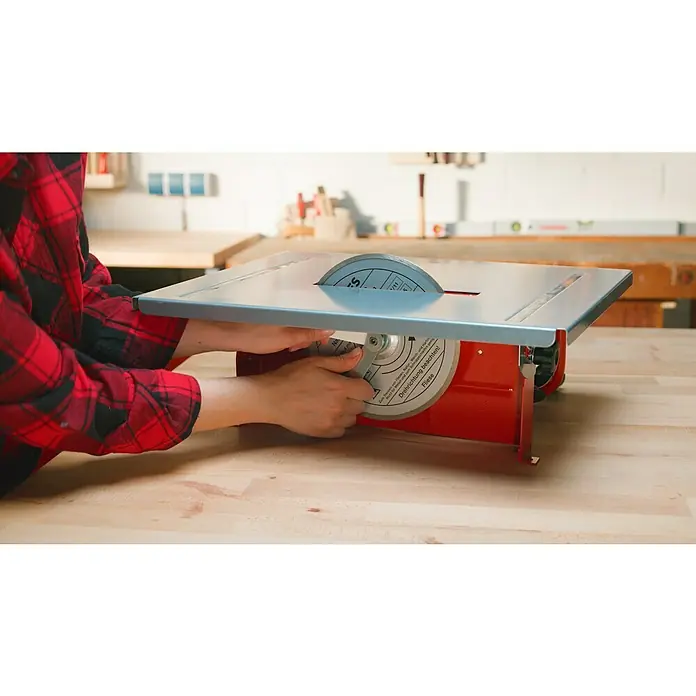 Herkules Elektro-Fliesenschneider H-FS 900 - 900 W, Schnitttiefe bei 90 °: 41 mm - Auf dem Foto ist eine Fliesen-Schneidmaschine zu sehen, an der eine Person arbeitet. Sie justiert die Scheibe, bevor sie Fliesen schneidet.