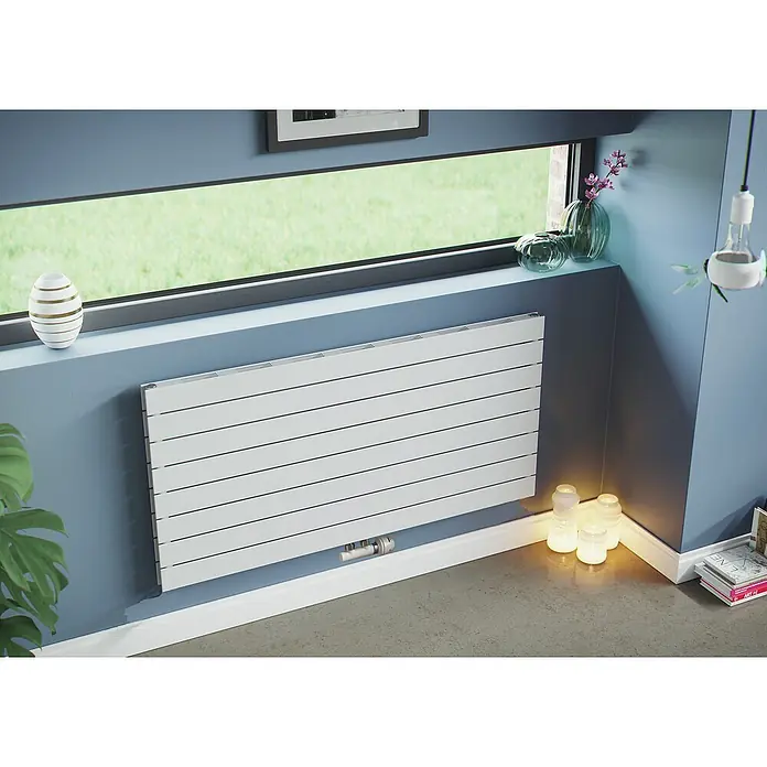 Ximax Raumheizkörper P1 Duplex Slimline Deluxe - B x H: 1.400 x 595 mm, Wärmeleistung bei Vorlauftemperatur von 75 °C (D: 50): 1.276 W - Ein horizontaler Heizkörper unter einem Fenster mit Dekorationen, der Wärme und Stil in den Raum bringt.