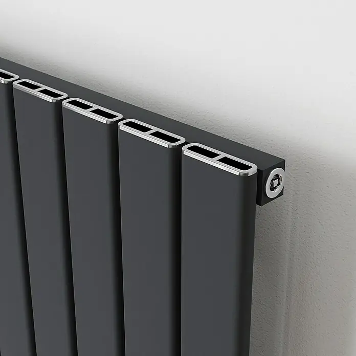 Ximax Designheizkörper Levis - B x H: 415 x 1.800 mm, Wärmeleistung bei Vorlauftemperatur von 75 °C (D: 50): 822 W, Anthrazit - Nahaufnahme eines modernen, schwarzen Heizkörpers mit silbernen Akzenten an einer weißen Wand.