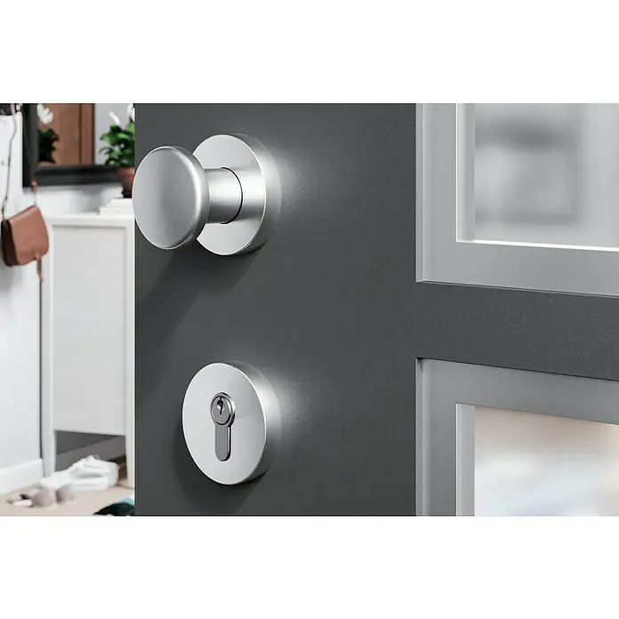 Portaferm Knopfdrücker - Vierkantstift: 8 mm, Silber - Nahaufnahme eines modernen Türgriffs und Schlosses aus Metall, die in einer dunklen Tür installiert sind.