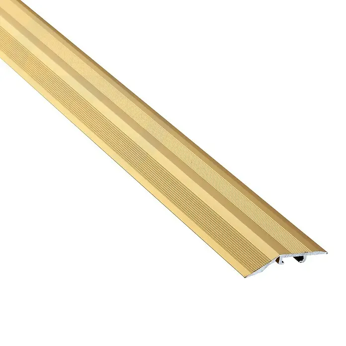 Perfil de transición Oro - Aluminio, Oro - Primer plano de una tira de transición dorada para pisos. La tira es acanalada y tiene una ranura en la parte inferior para una fácil instalación.