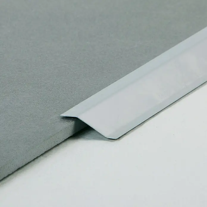 Perfil de transición Plateado - Acero, Plateado - Detalle de un borde de baldosa gris con un perfil de esquina blanco, ofreciendo un acabado limpio y protegiendo las baldosas.