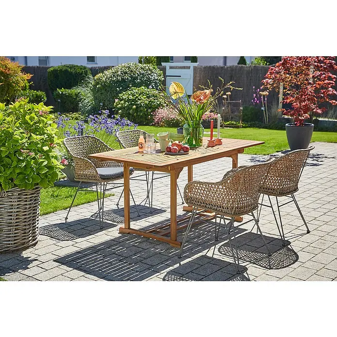Sunfun Gartenmöbel-Set Diana/Maja - 5 -tlg., Akazie/Stahl/PE-Geflecht, Gartentisch erweiterbar, Braun/Grau - Ein Gartentisch-Set mit vier Korbstühlen steht auf einer Terrasse, dekoriert mit Blumen, Obst und Getränken.