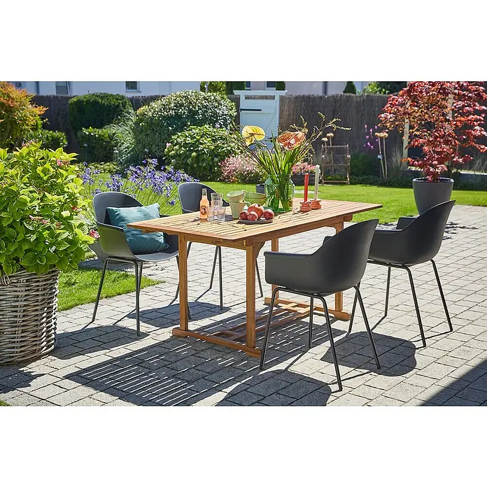 Sunfun Gartenmöbel-Set Diana/My - 5 -tlg., Akazie/Stahl/Kunststoff, Braun/Schwarz - Ein rechteckiger Gartentisch aus Holz mit vier schwarzen Stühlen auf einer gepflasterten Terrasse mit üppigem Grün im Hintergrund.