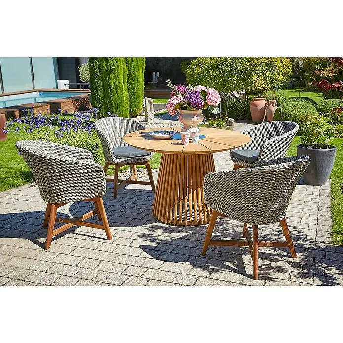 Sunfun Pauline Gartensessel - B x T x H: 62 x 70 x 80 cm, Polyrattan, Akazie, Bambus Grey/Naturbraun - Ein runder Holztisch mit vier Korbsesseln auf einer gepflasterten Terrasse mit grüner Umgebung. Perfekt für entspannte Stunden im Freien!
