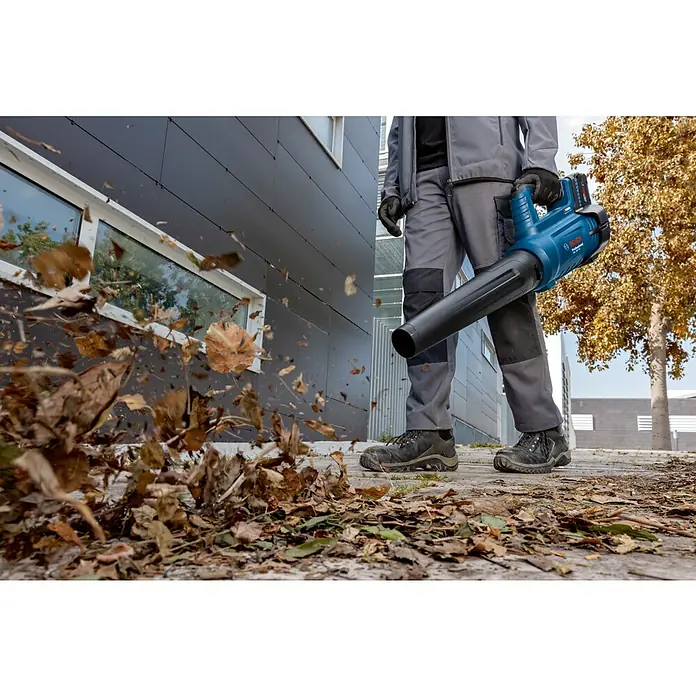Bosch Professional AMPShare 18V Akku-Gebläse GBL 18V-750 - 18 V, Ohne Akku, Blasgeschwindigkeit: 198 km/h - Ein Mann benutzt einen Bosch Akku-Laubbläser, um Herbstlaub von einem Gehweg zu entfernen. Der Laubbläser ist blau und hat einen schwarzen Auslass.