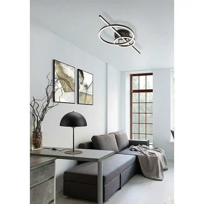 Trio Leuchten Tischleuchte rund Nola - 28 W, Ø x H: 20 x 30 cm, Schwarz matt, E14 - Eine moderne Wohnzimmeransicht mit einer auffälligen, kreisförmigen LED-Deckenleuchte, die das minimalistische Design des Raumes ergänzt.