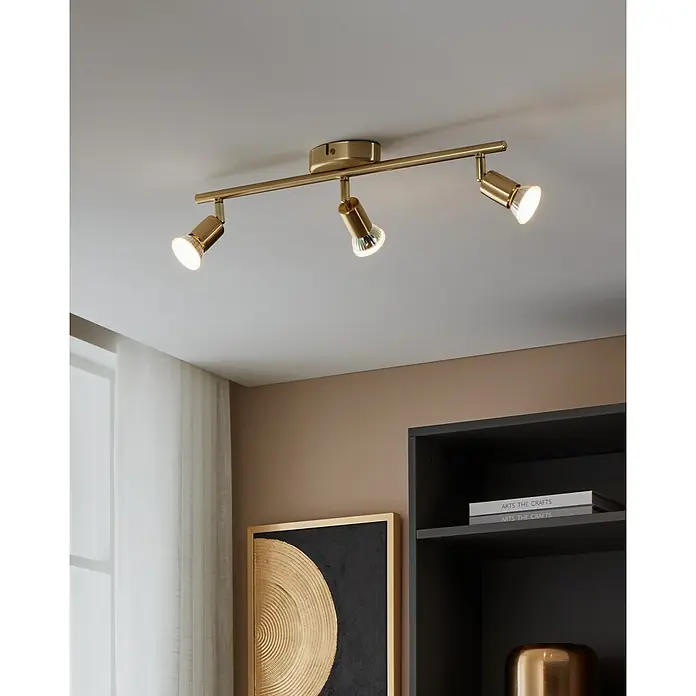 Eglo Buzz-LED Deckenstrahler BUZZ-LED - 8,4 W, Gold, GU10, 3 Stk. - Nahaufnahme einer goldenen Deckenleuchte mit drei Strahlern, die ein warmes Licht in einem modern eingerichteten Raum verbreiten.