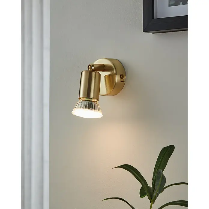 Eglo Buzz-LED Deckenstrahler BUZZ-LED - 2,8 W, Gold, GU10, 1 Stk. - Nahaufnahme einer Wandleuchte aus gebürstetem Gold mit einem klaren, geriffelten Glasschirm, die ein warmes Licht ausstrahlt.