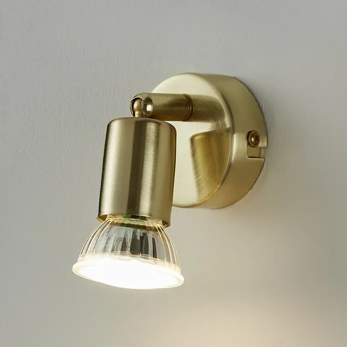 Eglo Buzz-LED Deckenstrahler BUZZ-LED - 2,8 W, Gold, GU10, 1 Stk. - Nahaufnahme einer goldenen Wandleuchte mit klarem Lampenschirm, die ein warmes Licht ausstrahlt.