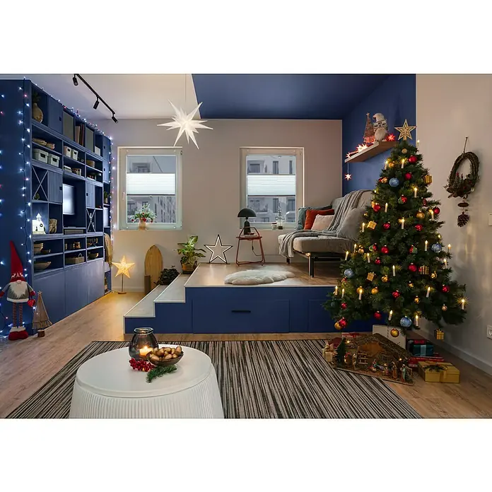 SCHÖNER WOHNEN-Farbe Wandfarbe DesignfarbeSanftes Seidengrau, Matt, 100 ml, Konservierungsmittelfrei - Festliches Wohnzimmer mit Weihnachtsbaum, Sternenlichtern und blauen Akzenten, die eine warme, winterliche Atmosphäre schaffen.
