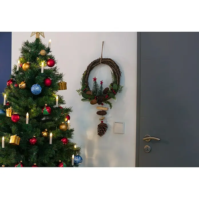 Türkranz - Rot/Braun/Grün, 57 cm - Weihnachtliche Szene mit geschmücktem Baum und festlichem Kranz an der Wand, die eine warme und einladende Atmosphäre ausstrahlen.