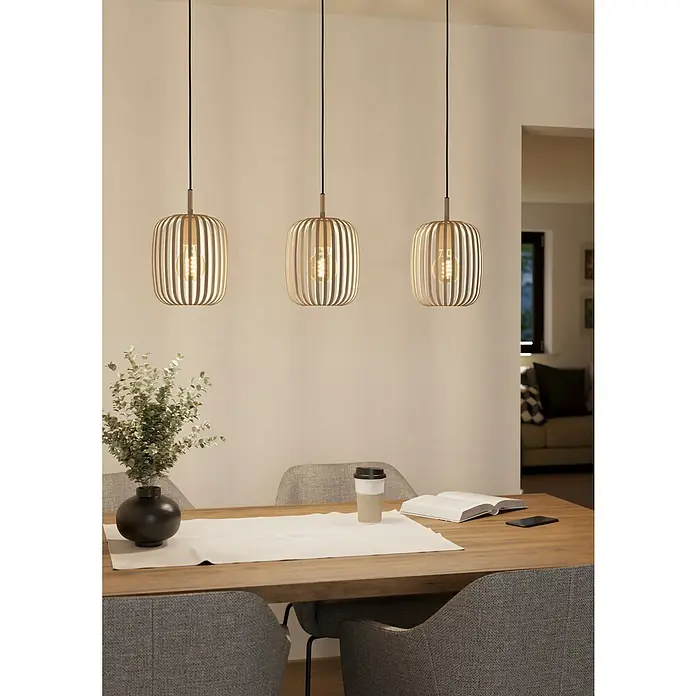 Eglo Romazzina Pendelleuchte - 120 W, Sand, E27, Anzahl Leuchtmittel: 3 Stk. - Drei hölzerne Pendelleuchten hängen über einem Esstisch, der mit einer Vase, einem Buch und einer Tasse dekoriert ist.