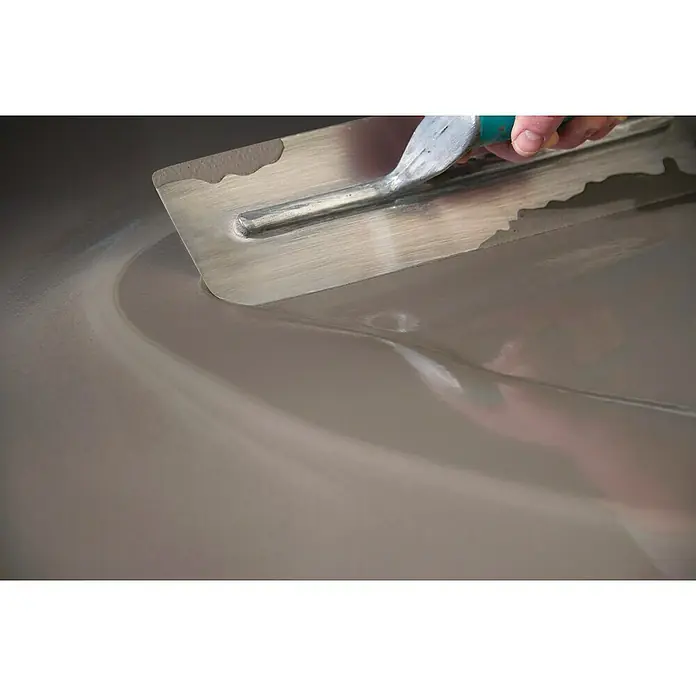 Kerakoll Mortero Autonivelante Planogel Rheo - 20 kg, Espesor: 1 mm - 30 mm - Primer plano de una llana aplicando compuesto autonivelante sobre una superficie plana para superficies lisas.