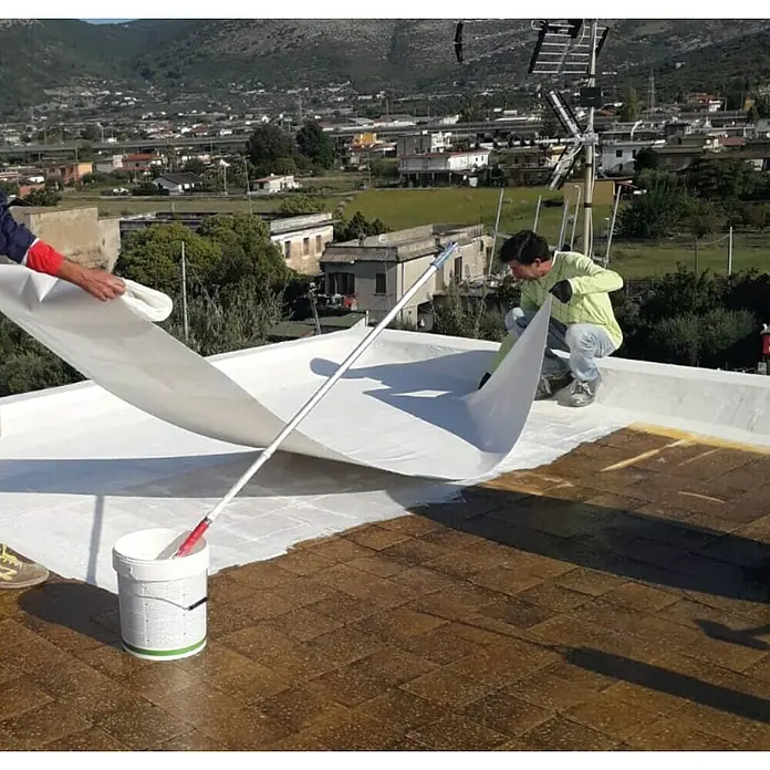 Kerakoll Malla de refuerzo Bioscud TNT - 1 x 50 m - Dos personas instalan una membrana impermeable para techos, ayudadas por un bote de pintura y un rodillo, para proteger el techo de los daños climáticos.