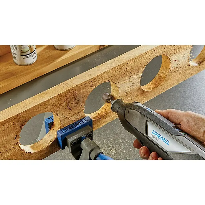 Dremel Akku-Multifunktionswerkzeug 8240-3/45 - 12 V, 1 Akku, 2 Ah, Inkl. 3 Aufsätzen und 45 Zubehören - Eine Nahaufnahme eines Dremel 8240 Multifunktionswerkzeugs beim Schleifen eines Holzes, das mit einer Dremel-Klemme befestigt ist.